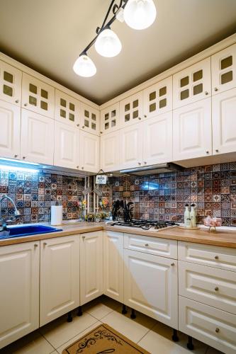 a kitchen with white cabinets and a tile wall at The QUARK Modern Designed 2BR Central Apartment in Craiova