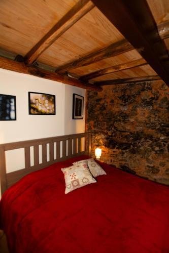 a red bed in a room with a brick wall at Casa da Mata de Fajão in Pampilhosa da Serra