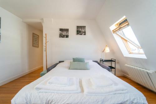 - une chambre dotée d'un grand lit avec des draps blancs et une fenêtre dans l'établissement Le Céleste Wifi Sacré-Cœur, à Paris