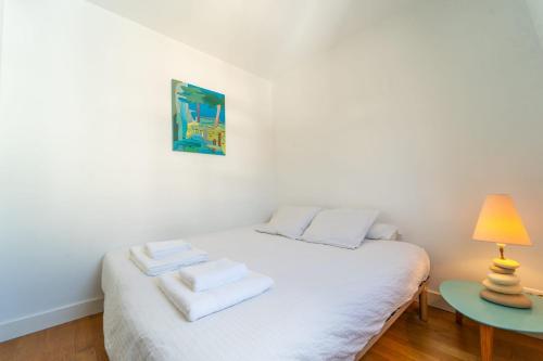 une chambre avec un lit blanc avec des serviettes dessus dans l'établissement Le Céleste Wifi Sacré-Cœur, à Paris