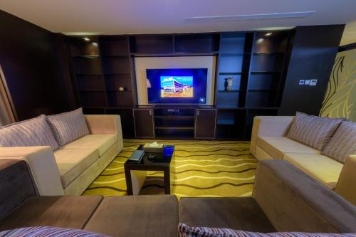 a living room with couches and a flat screen tv at National Park Hotel in Baljurashi