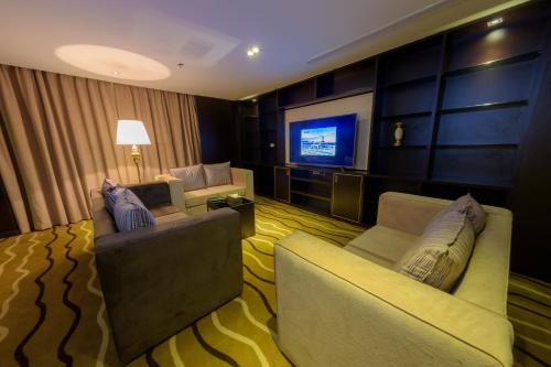 a living room with two chairs and a flat screen tv at National Park Hotel in Baljurashi