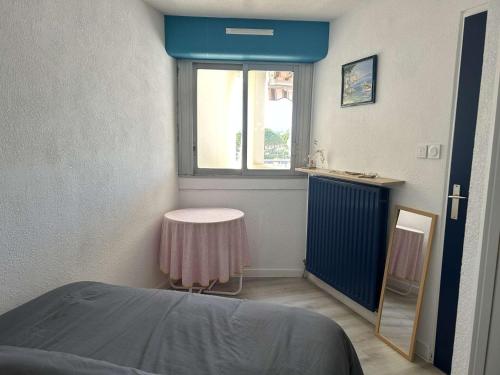 Cette petite chambre dispose d'une table et d'une fenêtre. dans l'établissement Appartement rénové, 4 couchages, proche plage et commerces, parking privé, Port Camargue - FR-1-250-44, au Grau-du-Roi
