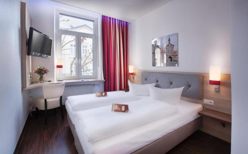 a hotel room with a large white bed and a window at Hotel National in Bamberg