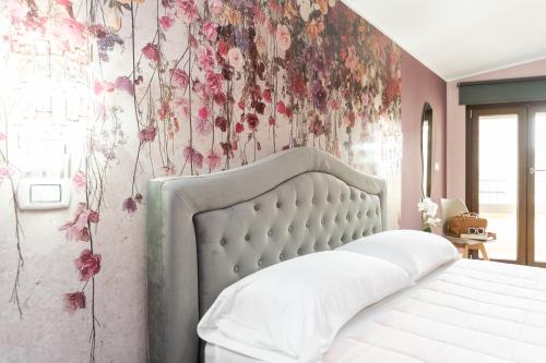a bedroom with a white bed with flowers on the wall at B&B Golden House & spa in Rose