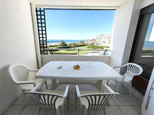 d'une table et de chaises blanches sur un balcon avec vue sur l'océan. dans l'établissement Superbe T3 lumineux à 30m de la plage, 6 pers, ascenseur, parking - FR-1-607-5, au Cap d'Agde