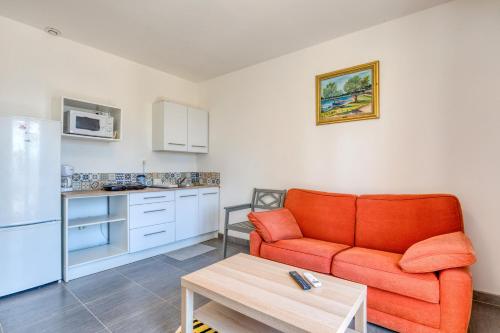 Il comprend un salon avec un canapé orange et une cuisine. dans l'établissement Appartement 4 personnes, à Poussan