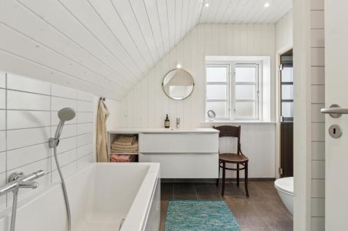 a bathroom with a tub and a sink and a mirror at Feriehus 1107 in Ringkøbing