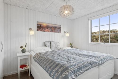 a white bedroom with a bed and a window at Feriehus 1103 in Ringkøbing