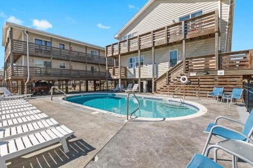 a patio with a pool and chairs and a building at 2BR Condo w Pool Beach Access and Walk to Hangout in Gulf Shores