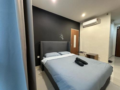 a bedroom with a bed with two black pillows on it at Cozy Stays Studio C - Kozi Square Kuching in Kuching