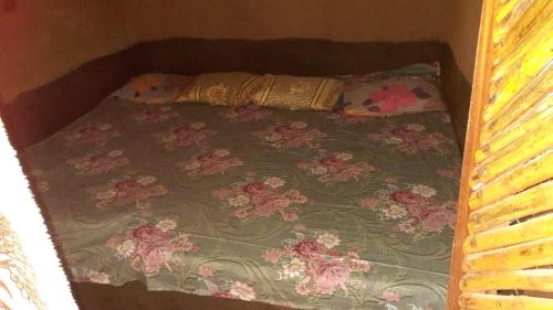 a small bed with a floral bedspread and pillows on it at Abimansala Resort in Hunnasgiriya