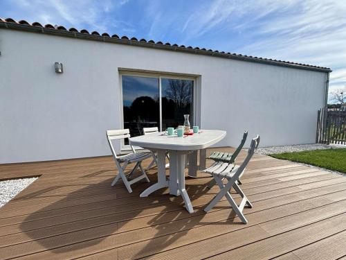une table et des chaises blanches sur une terrasse en bois dans l'établissement Maison neuve au calme, proche plage et commerces, 4 couchages, jardin, garage - Dolus-d'Oléron - FR-1-246A-298, à Dolus-d'Oléron