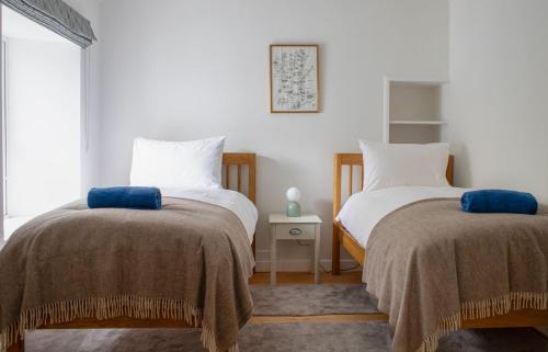 two beds in a room with white walls at The Old Post Office in Saasaig