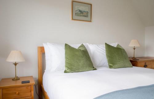 a bedroom with a white bed with green pillows at The Old Post Office in Saasaig