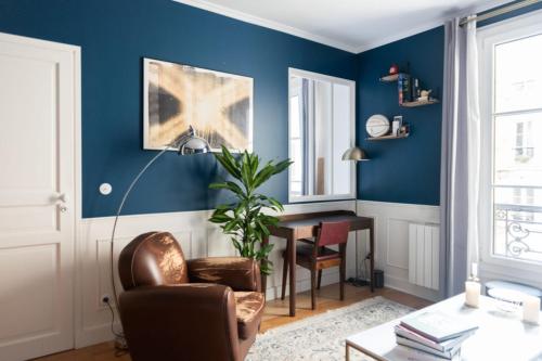 un salon avec des murs bleus, une chaise et une table dans l'établissement Nice refurbished T2 near Place du Trocadéro, à Paris