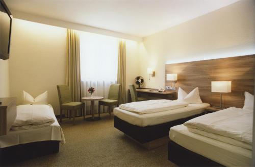 a hotel room with two beds and a desk at Hotel Jedermann in Munich