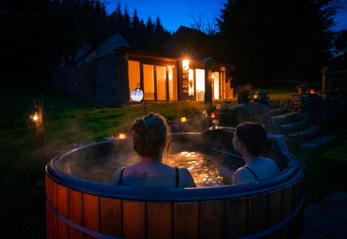 two people sitting in a hot tub at night at Self Contained Yurt - Barbadoes in Tintern