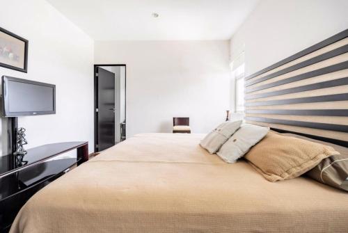 a bedroom with a large bed and a flat screen tv at Habitación confortable dentro departamento Natura in Mexico City