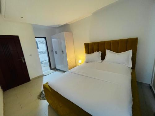 ein Schlafzimmer mit einem großen Bett mit weißen Laken und Kissen in der Unterkunft Mich appart in Jaunde