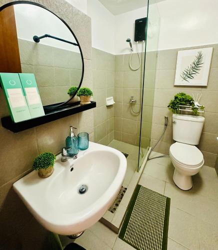 a bathroom with a sink and a toilet and a mirror at Mesatierra Garden Residence 2005 in Davao City