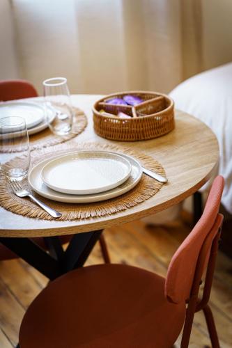 une table en bois avec des assiettes et un panier dans l'établissement Stud Cannelle 2pers Wi-Fi, à Cambrai