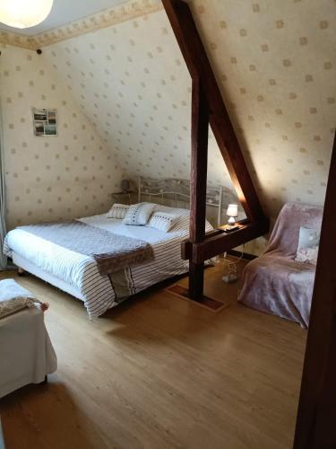 une chambre avec un grand lit dans un grenier dans l'établissement Maison d'hôtes Les Vallées, à Saint-Quentin-sur-le-Homme
