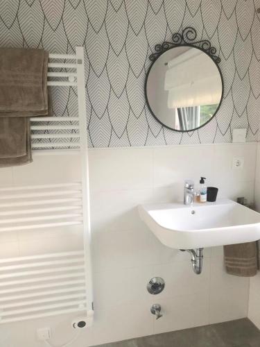 a white bathroom with a sink and a mirror at Apartment mit Blick ins Grüne in Mitterfels