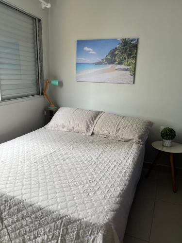 a bed in a bedroom with a picture of a beach at Apto Tombo Guarujá 2quartos pé na areia e vaga in Guarujá