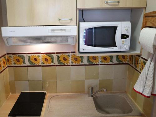 une cuisine avec un micro-ondes et un évier dans l'établissement Appartement rénové 6 pers, au pied des pistes - FR-1-322-159, aux Orres