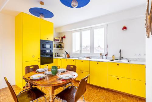 une cuisine jaune avec une table et des chaises en bois dans l'établissement GuestReady - Colorful Family Getaway in Belleville, à Paris