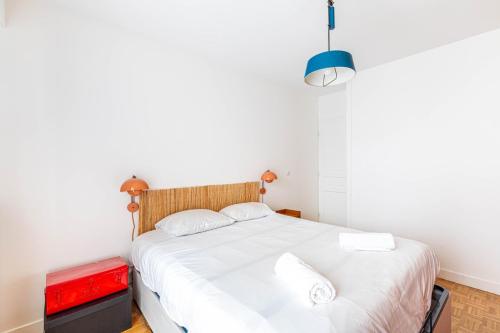 - une chambre avec un grand lit blanc et un tronc rouge dans l'établissement GuestReady - Colorful Family Getaway in Belleville, à Paris