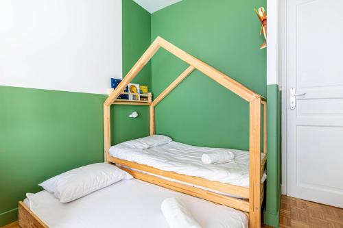 - une chambre avec 2 lits superposés dans un mur vert dans l'établissement GuestReady - Colorful Family Getaway in Belleville, à Paris