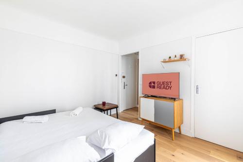 une chambre blanche avec un lit et une télévision dans l'établissement GuestReady - Sleek and Comfy Stay near the metro, à Paris