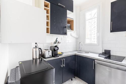 - une cuisine avec des placards noirs et un évier dans l'établissement GuestReady - Sleek and Comfy Stay near the metro, à Paris
