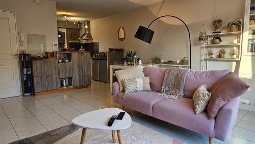 un salon avec un canapé rose et une cuisine dans l'établissement Maison - plescop - jardin - wifi, à Plescop