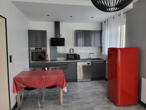 une cuisine avec une table et un réfrigérateur rouge dans l'établissement Chez Marie et Marc, à Luchon
