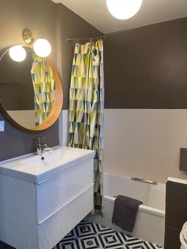 une salle de bain avec un lavabo, un miroir et une baignoire dans l'établissement La Maison de Marie à 5 minutes à pied de la Plage avec Parking privée et gratuit, à Lion-sur-Mer