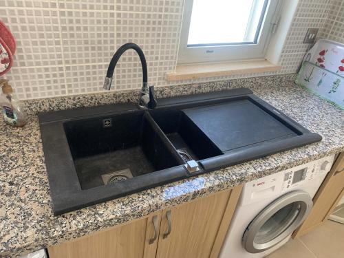 a black sink in a kitchen with a washing machine at Boho Bay Apartment in Akanthou