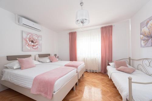 Apartman Rita with pool في قشتيلا: سريرين في غرفة بيضاء مع وسائد وردية