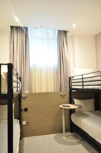 a bedroom with two bunk beds and a window at Heeton Concept Hotel - Kensington London in London