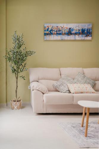 a white couch in a living room with a tree at Apartamento Don Marcos B in Badajoz