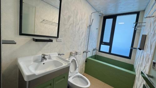 a bathroom with a sink and a toilet and a window at 禾夏民宿Her Shot Inn in Hengchun