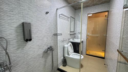a bathroom with a toilet and a glass door at 禾夏民宿Her Shot Inn in Hengchun