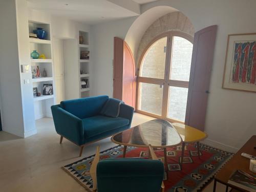 un salon avec un canapé bleu et une table en verre dans l'établissement Alma - Appartement au cœur du Palais des papes, à Avignon