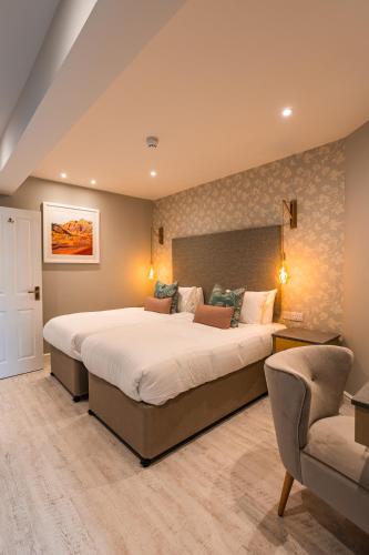 a large bedroom with two beds and a chair at Ambleside Townhouse in Ambleside