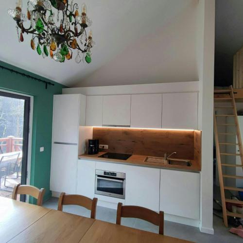 a kitchen with white cabinets and a chandelier at Au Bois Chantant in Somme-Leuze