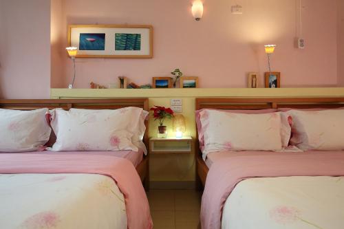 two beds in a room with pink walls at Huxi B&B in Jian