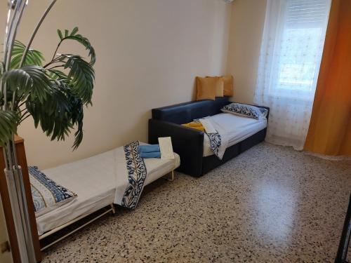 a room with two beds and a couch and a plant at Room&Board 2 Bedrooms up to 7 beds 1 Bathroom in Voghera