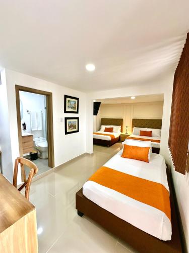 a hotel room with two beds and a bathroom at Hotel Cafe Cafe Avenida in Armenia